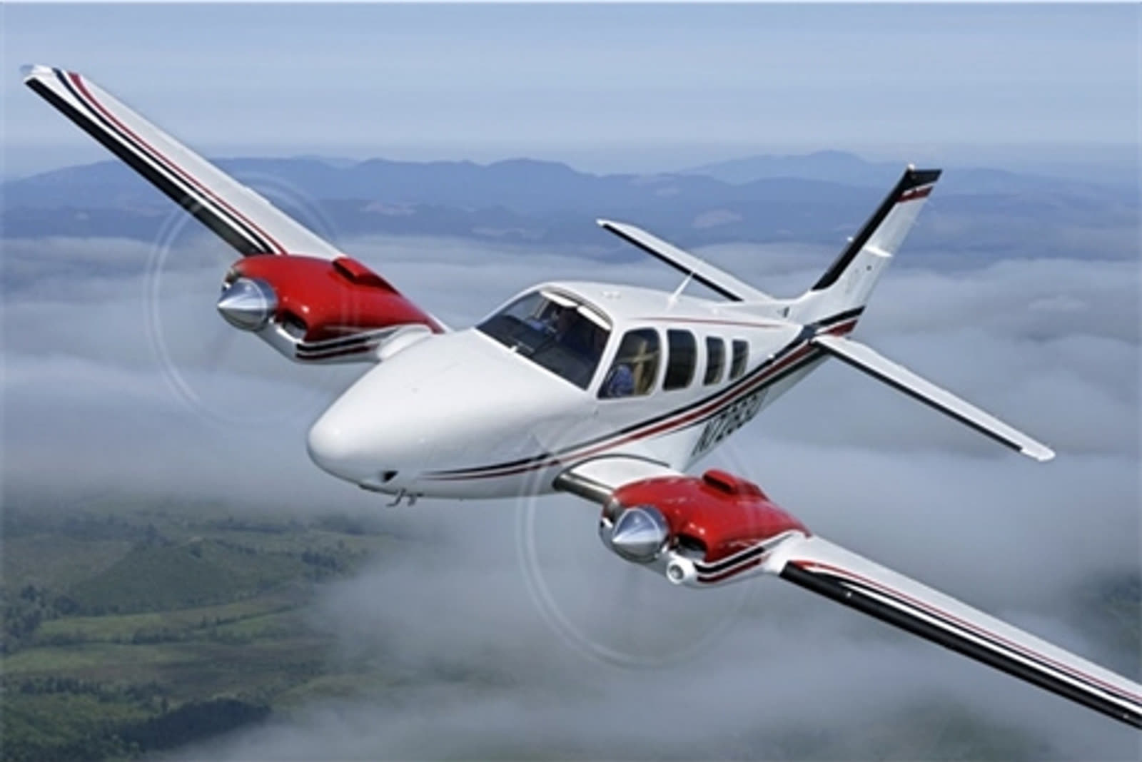 Avião bimotor branco e vermelho voando acima das nuvens, sobre montanhas