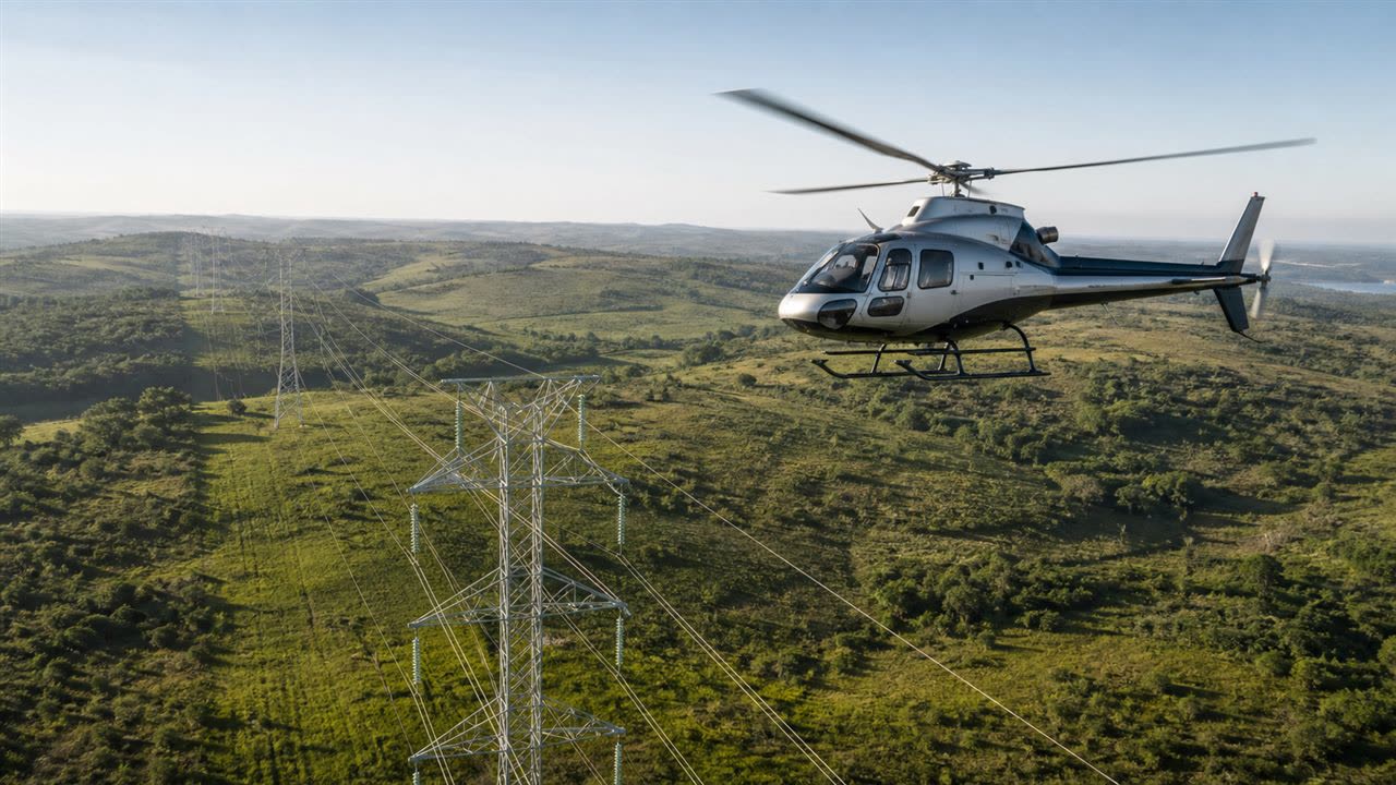 Helicóptero monomotor sobrevoando linha de transmissão de energia em região de morros