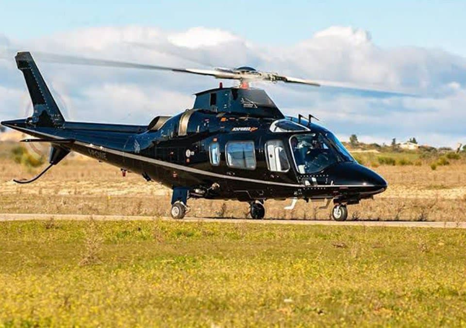 Helicóptero bimotor executivo preto taxiando em pista cercada de vegetação rasteira