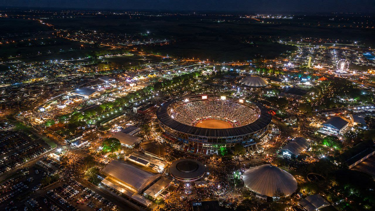 Arena de rodeio lotada e iluminada à noite em Barretos, vista do alto com o parque ao redor
