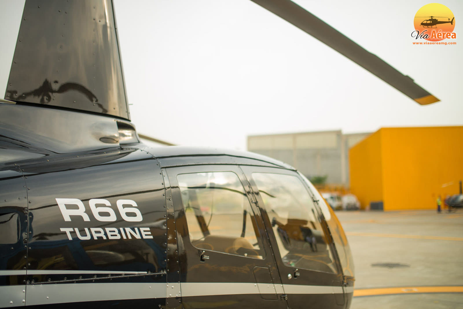 Detalhe da fuselagem preta de um helicóptero monomotor estacionado no pátio do hangar
