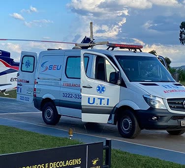 Ambulância UTI de portas abertas aguardando o paciente ao lado do helicóptero no heliponto